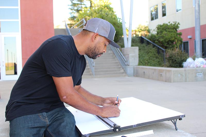 Man outside at Butte College drafting at a drafting table